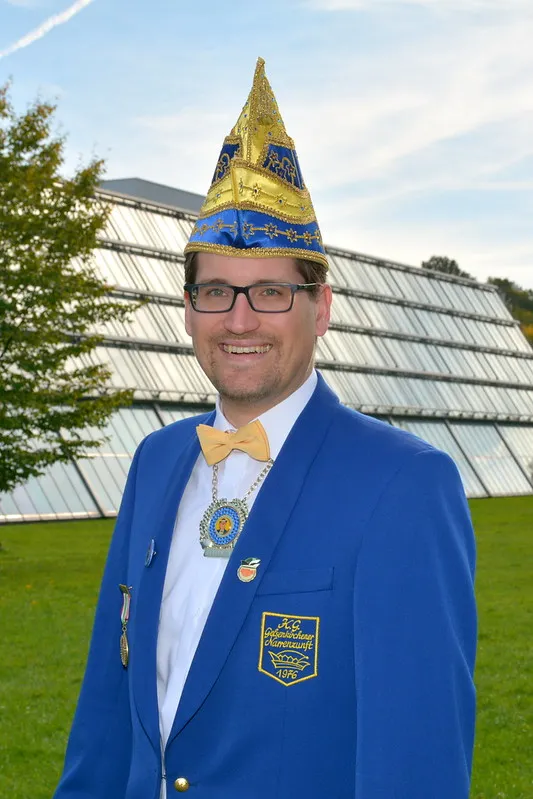 Porträt von Marius Stange im blauen Sitzungsjackett mit Narrenkappe