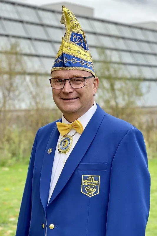 Porträt von Martin Gemsa im blauen Sitzungsjackett mit Narrenkappe